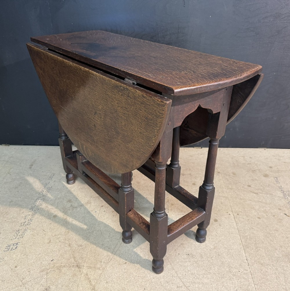 An eighteenth-century dark oak gateleg table featuring an oval drop-leaf top supported by turned legs and stretchers. View IV