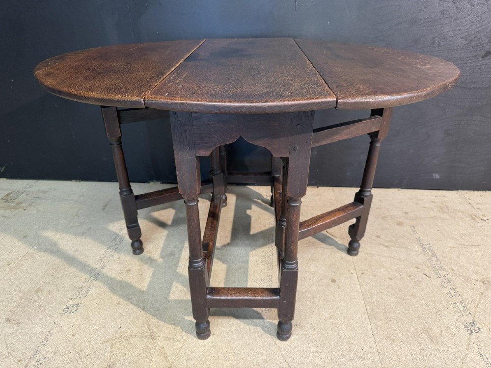 An eighteenth-century dark oak gateleg table featuring an oval drop-leaf top supported by turned legs and stretchers. View V
