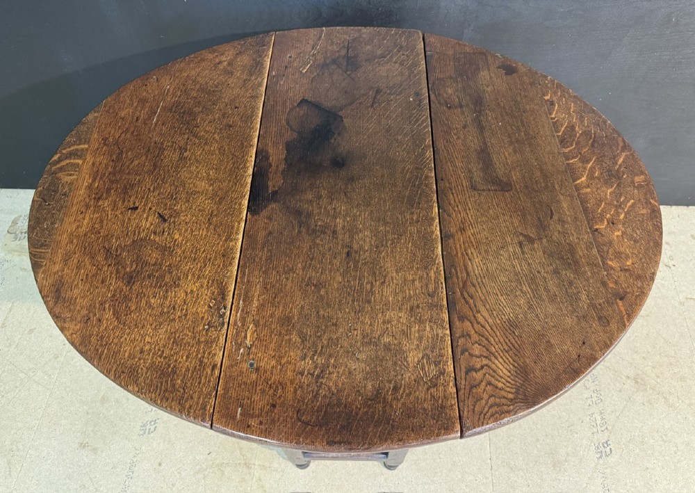An eighteenth-century dark oak gateleg table featuring an oval drop-leaf top supported by turned legs and stretchers. View VI