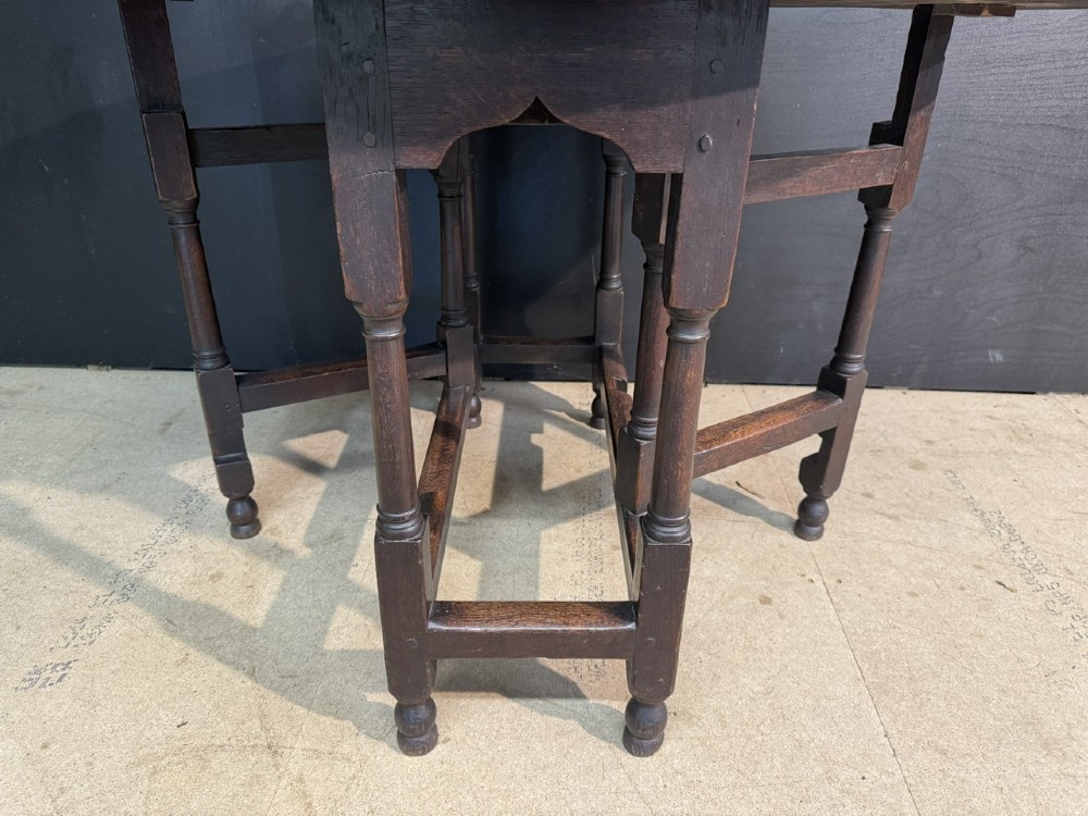 An eighteenth-century dark oak gateleg table featuring an oval drop-leaf top supported by turned legs and stretchers. View VII