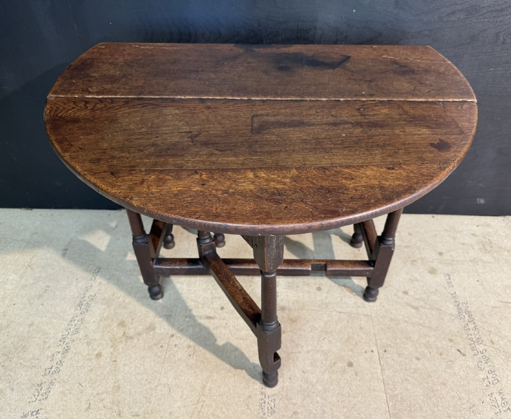 An eighteenth-century dark oak gateleg table featuring an oval drop-leaf top supported by turned legs and stretchers. View X