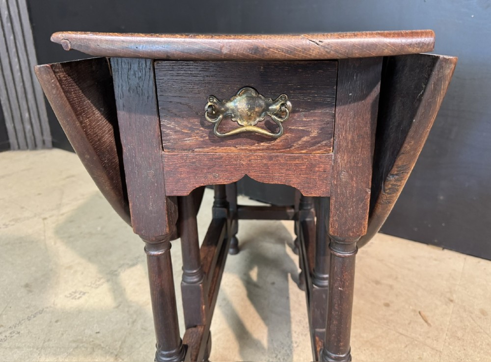 An eighteenth-century dark oak gateleg table featuring an oval drop-leaf top supported by turned legs and stretchers. View XIII