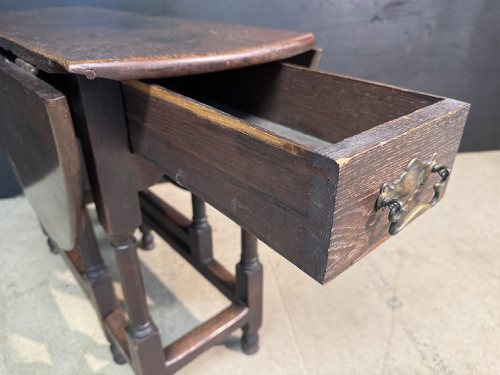An eighteenth-century dark oak gateleg table featuring an oval drop-leaf top supported by turned legs and stretchers. View XV