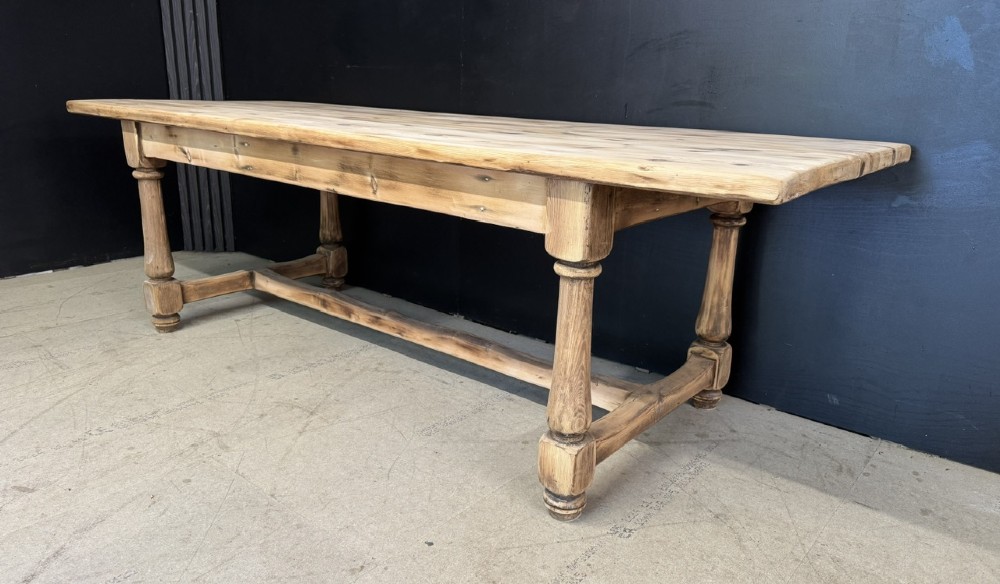A large antique natural pine dining table featuring turned legs connected by a low H-stretcher and a solid plank top. View V