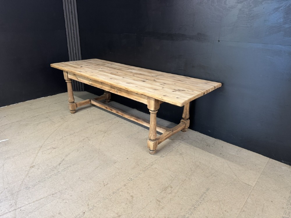 A large antique natural pine dining table featuring turned legs connected by a low H-stretcher and a solid plank top. View VI