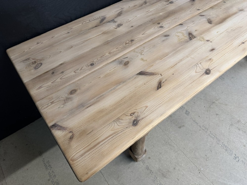 A large antique natural pine dining table featuring turned legs connected by a low H-stretcher and a solid plank top. View XI