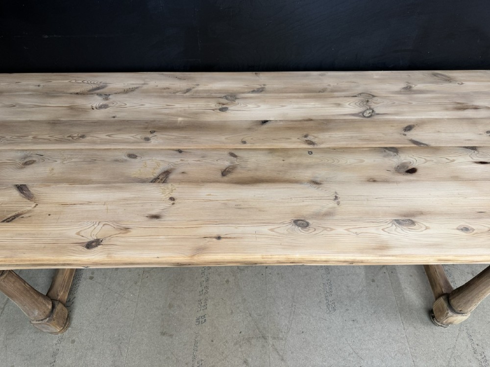 A large antique natural pine dining table featuring turned legs connected by a low H-stretcher and a solid plank top. View XIV