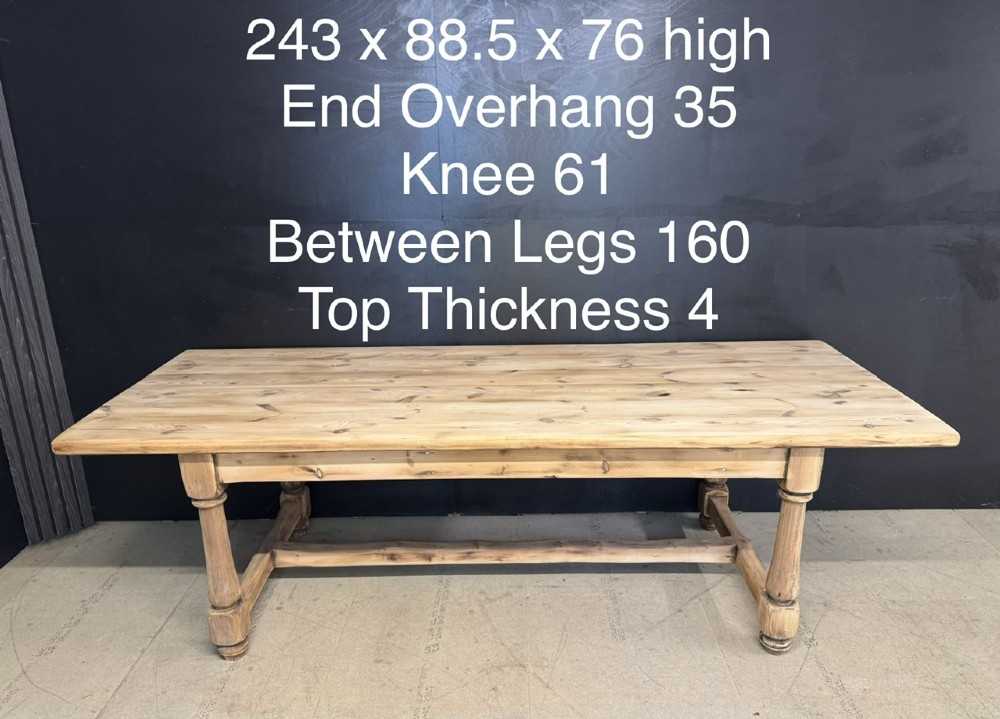 A large antique natural pine dining table featuring turned legs connected by a low H-stretcher and a solid plank top. View XV