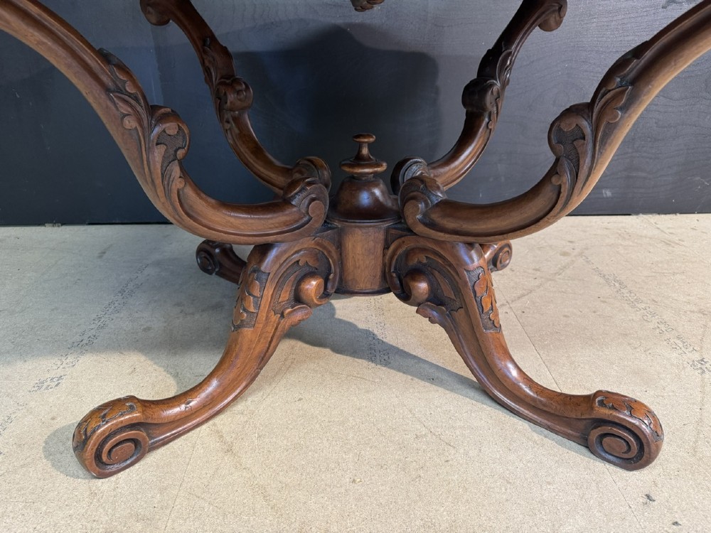 An antique burr walnut centre table featuring a shaped top, an intricately carved apron, and a quadruped pedestal base with scrolled feet. View III