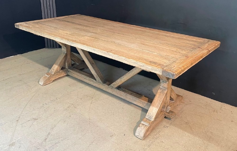 A large, pale pine farmhouse dining table featuring a solid timber top and a sturdy trestle-style base with diagonal bracing. View II