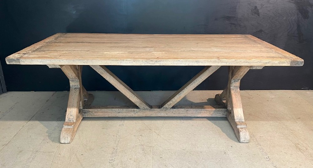 A large, pale pine farmhouse dining table featuring a solid timber top and a sturdy trestle-style base with diagonal bracing. View V