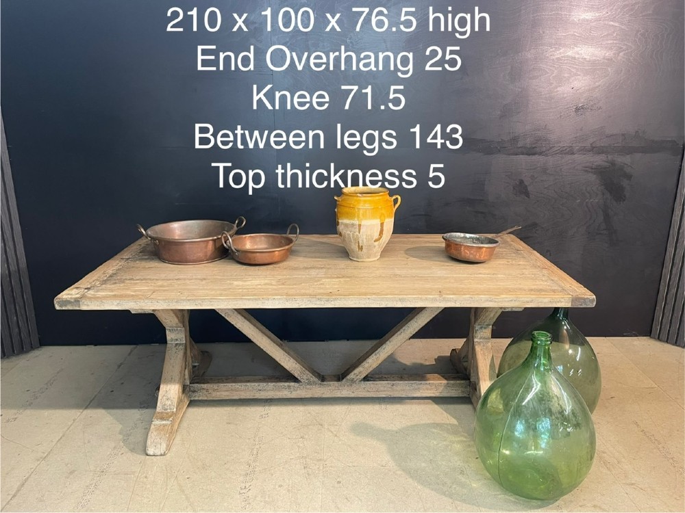 A large, pale pine farmhouse dining table featuring a solid timber top and a sturdy trestle-style base with diagonal bracing. View VI