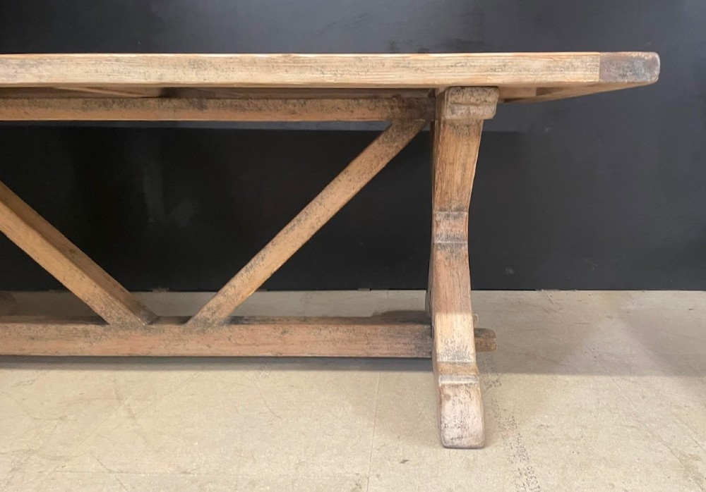 A large, pale pine farmhouse dining table featuring a solid timber top and a sturdy trestle-style base with diagonal bracing. View IX