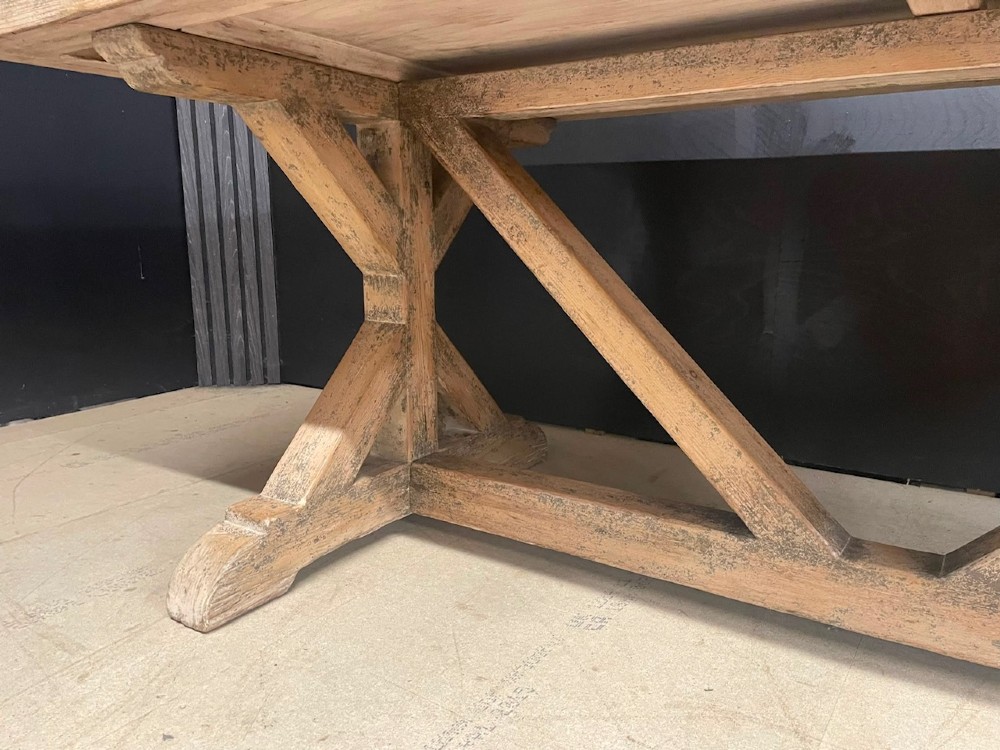 A large, pale pine farmhouse dining table featuring a solid timber top and a sturdy trestle-style base with diagonal bracing. View X