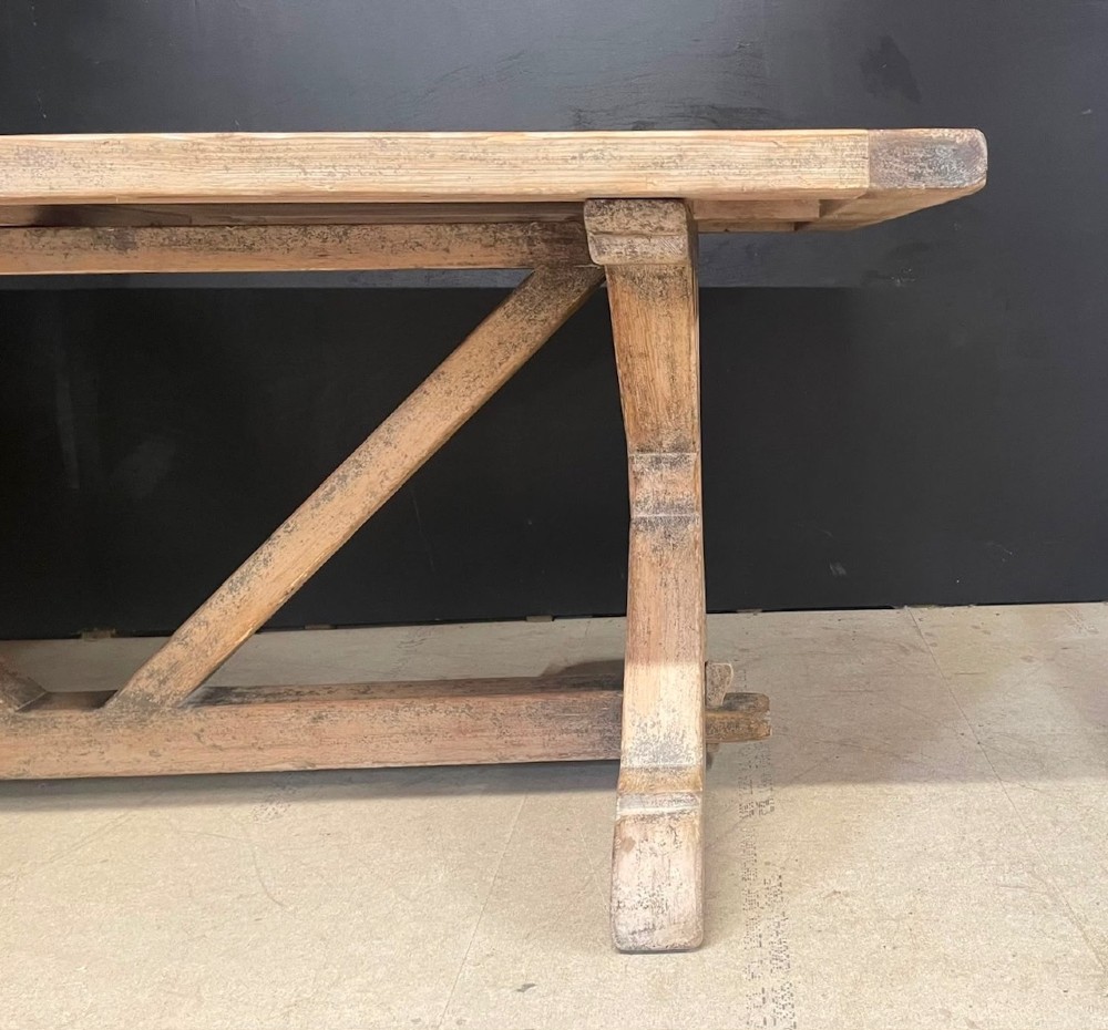 A large, pale pine farmhouse dining table featuring a solid timber top and a sturdy trestle-style base with diagonal bracing. View XII