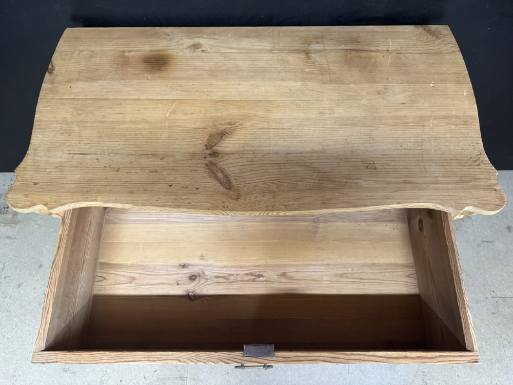 A three-drawer stripped pine chest of drawers featuring carved side corbels, brass drop handles, and turned bun feet. View XI