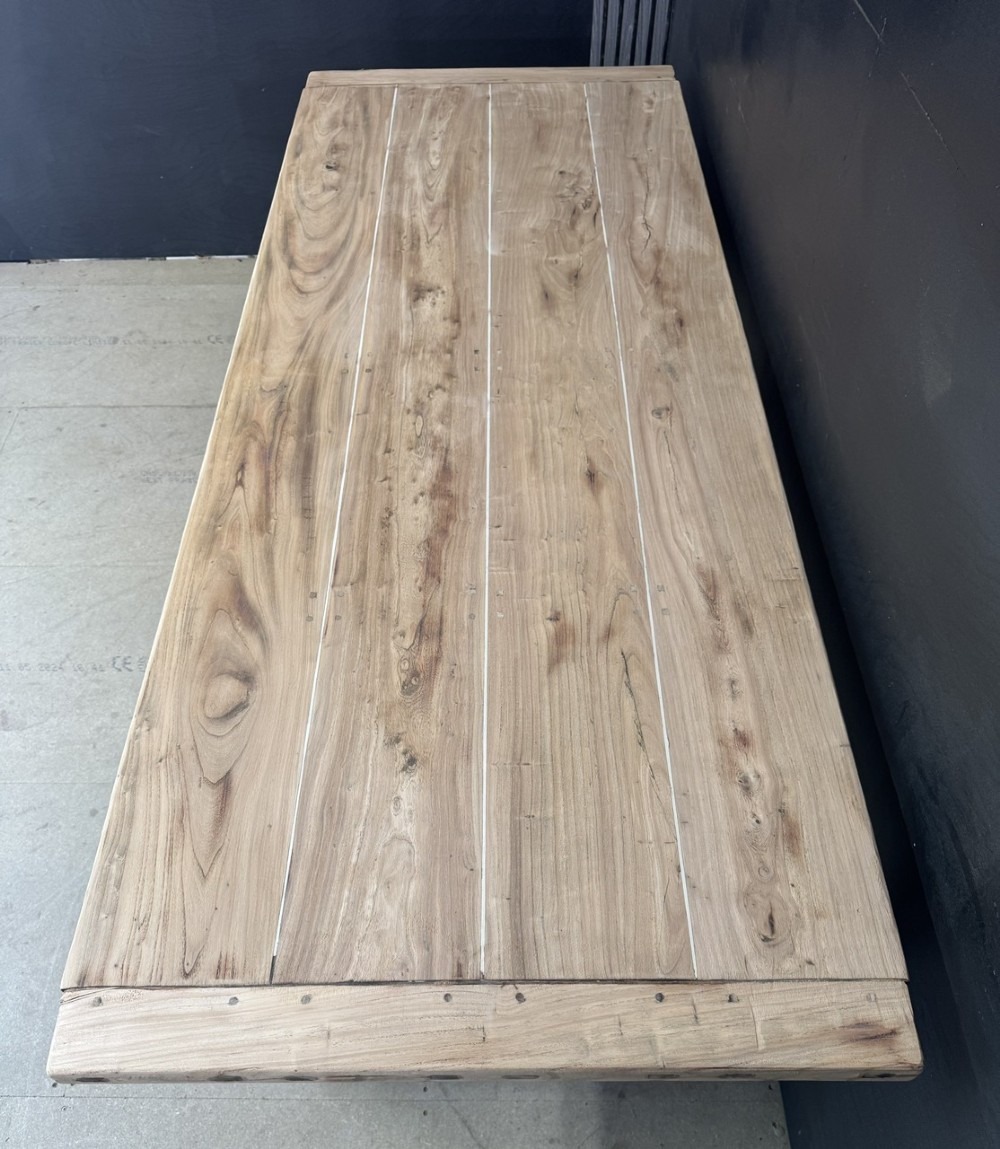 A rustic wooden dining table with a natural scrubbed timber top, carved apron frieze, turned legs, and a floor-level H-stretcher. View V