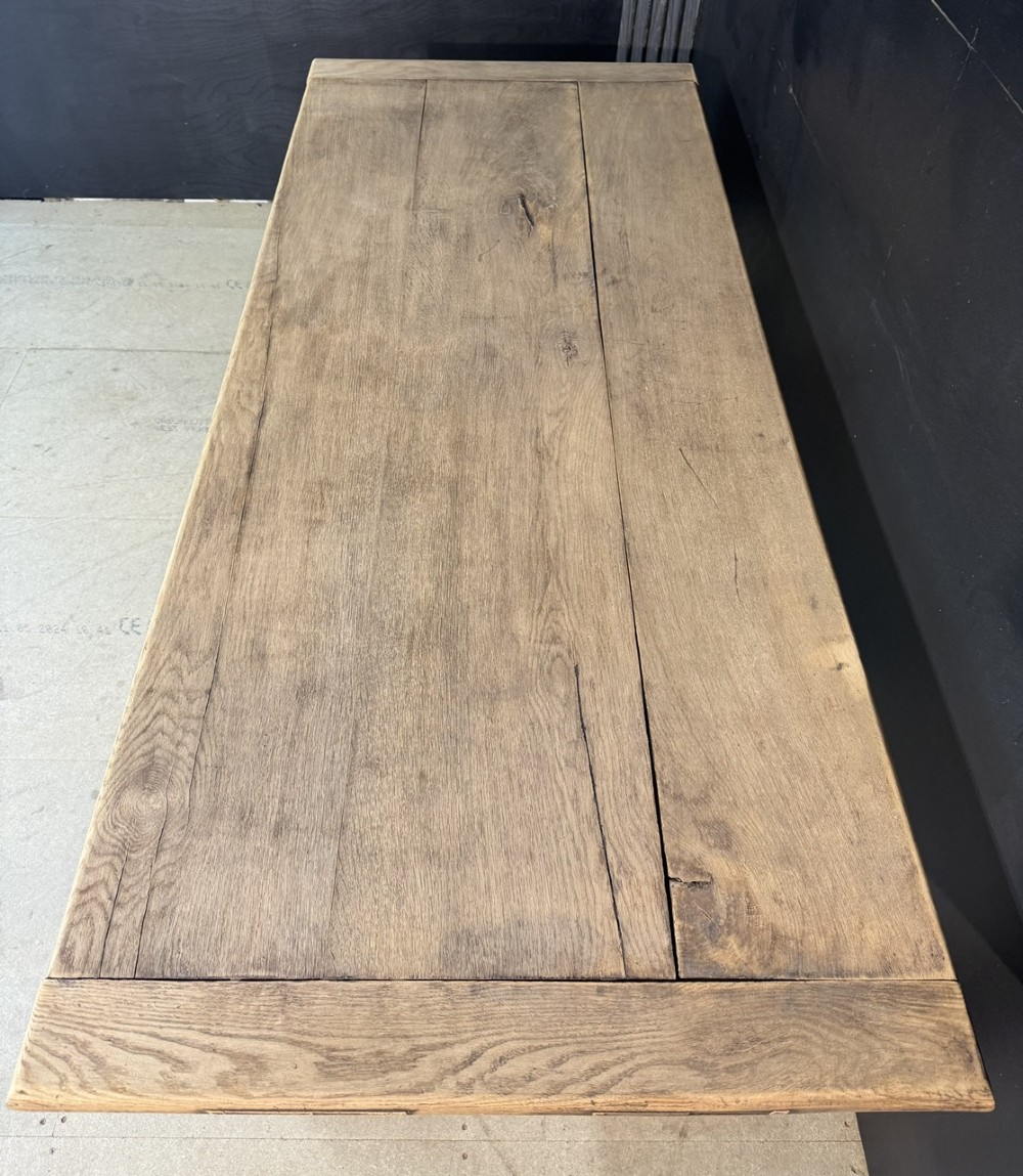 A rectangular bleached oak farmhouse dining table with turned legs, breadboard ends, and a low central stretcher base. View IV