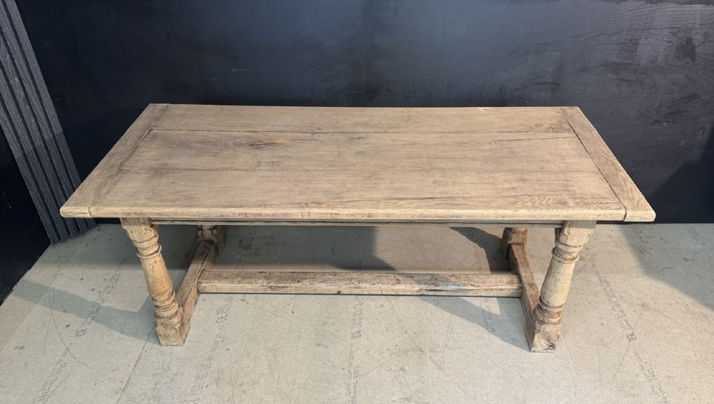 A rectangular bleached oak farmhouse dining table with turned legs, breadboard ends, and a low central stretcher base. View IX