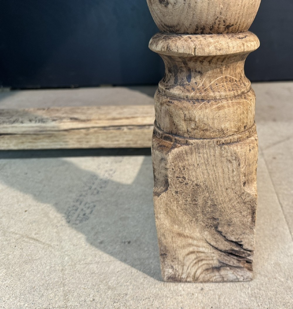 A rectangular bleached oak farmhouse dining table with turned legs, breadboard ends, and a low central stretcher base. View X