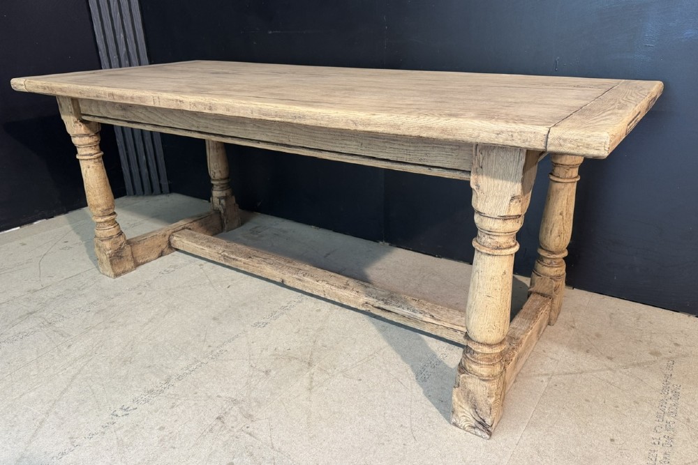 A rectangular bleached oak farmhouse dining table with turned legs, breadboard ends, and a low central stretcher base. View XI