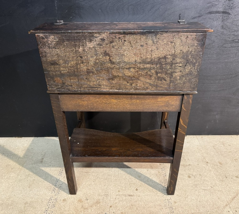 A 17th-century dark oak writing slope box on a wooden stand, featuring carved initials R S and a central iron lock plate. View X