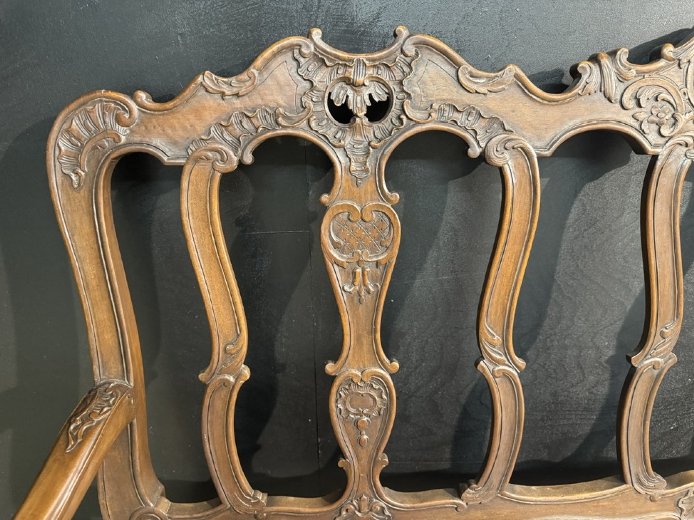 A carved walnut three-seater Rococo Revival settee featuring an openwork backrest with vertical splats and a blue and white patterned upholstered seat. View X