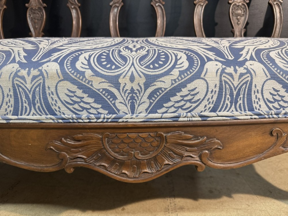 A carved walnut three-seater Rococo Revival settee featuring an openwork backrest with vertical splats and a blue and white patterned upholstered seat. View XI