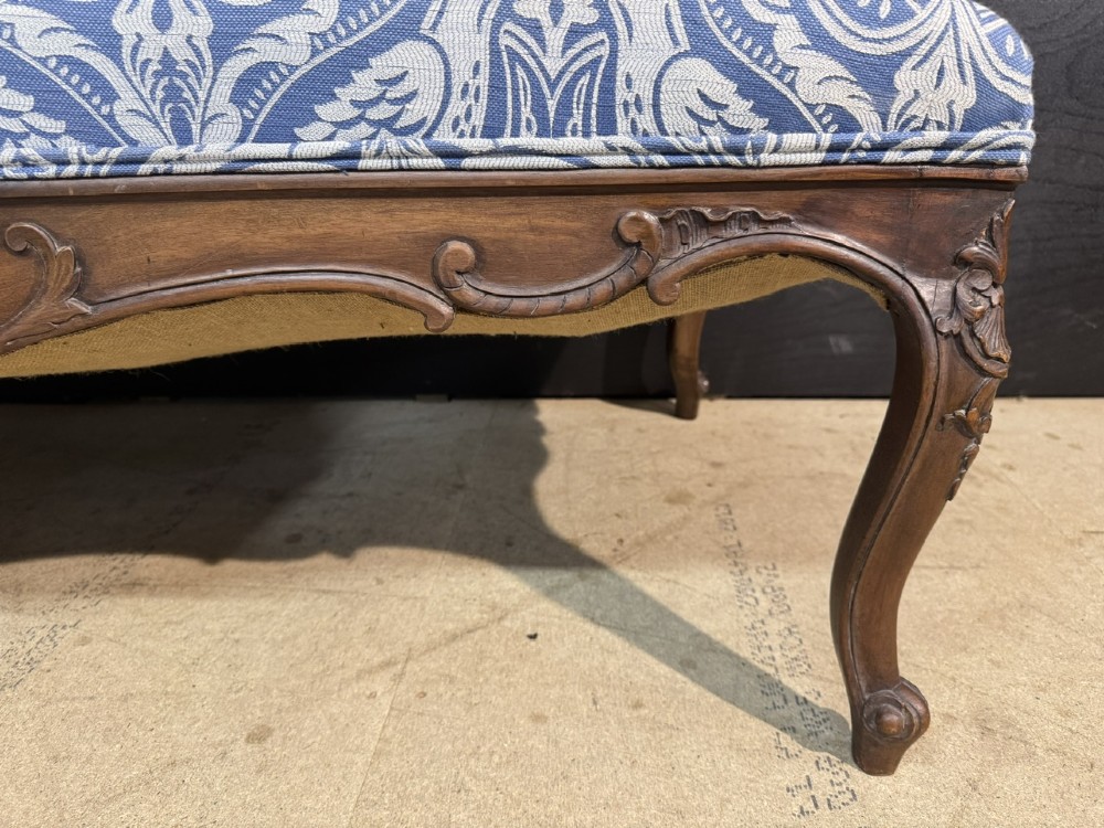 A carved walnut three-seater Rococo Revival settee featuring an openwork backrest with vertical splats and a blue and white patterned upholstered seat. View XII