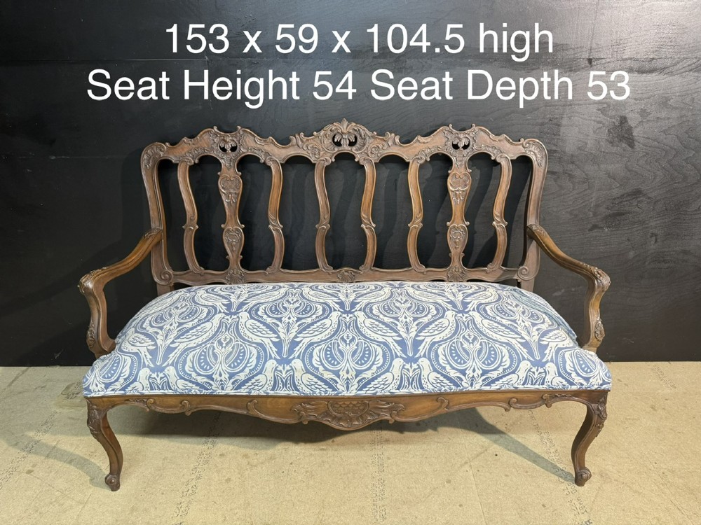 A carved walnut three-seater Rococo Revival settee featuring an openwork backrest with vertical splats and a blue and white patterned upholstered seat. View XIII