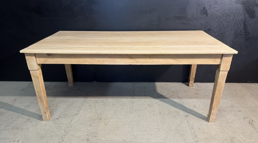 A rectangular light oak dining table featuring clean straight edges, a planked top, and simple tapered legs against a neutral background.