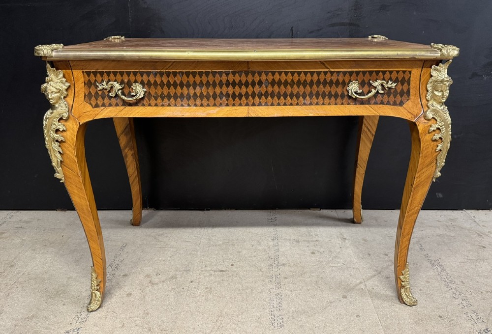 A French Louis XV style marquetry bureau plat featuring floral inlaid wood on the top surface, a diamond parquetry drawer frieze, gilt-bronze corner mounts, and curved cabriole legs. View II