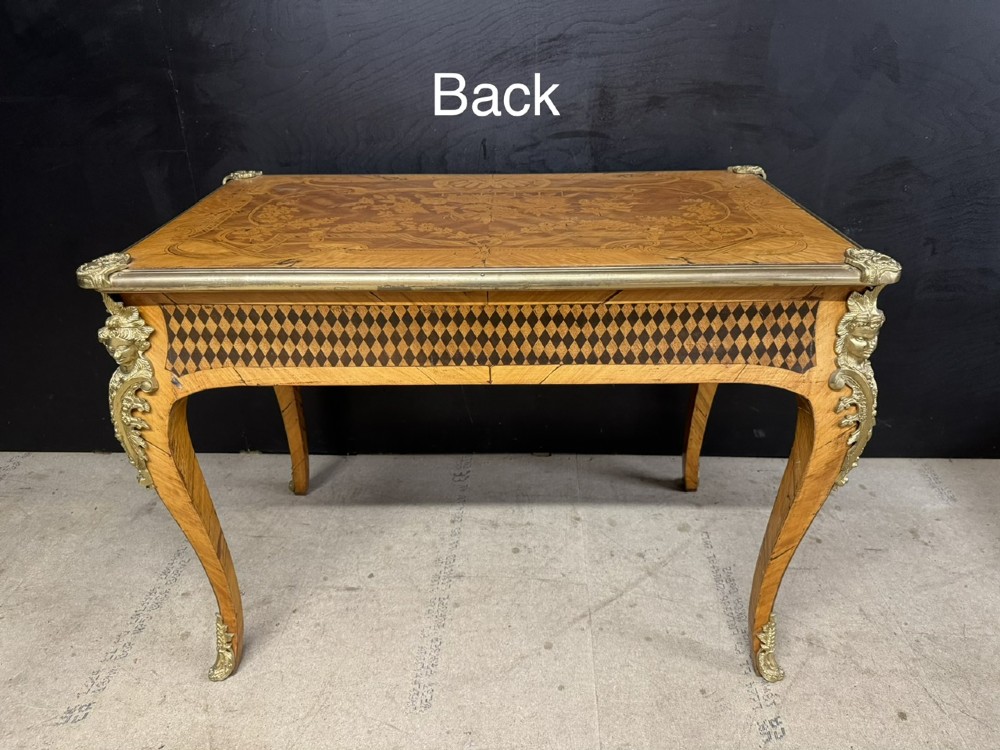 A French Louis XV style marquetry bureau plat featuring floral inlaid wood on the top surface, a diamond parquetry drawer frieze, gilt-bronze corner mounts, and curved cabriole legs. View XV