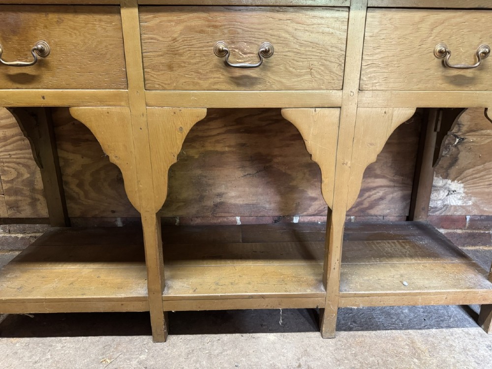 A two-part antique pine Welsh dresser featuring an open plate rack flanked by small side cupboards above three frieze drawers and an open pot board base. View XI