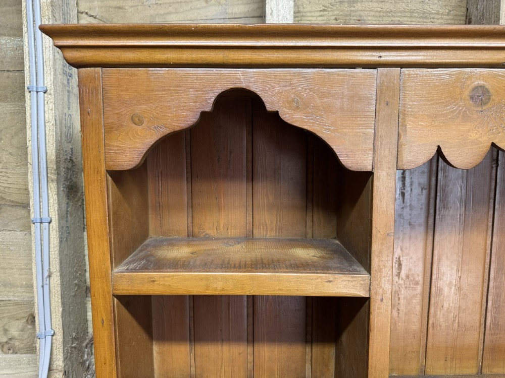 A two-part antique pine Welsh dresser featuring an open plate rack flanked by small side cupboards above three frieze drawers and an open pot board base. View XIII