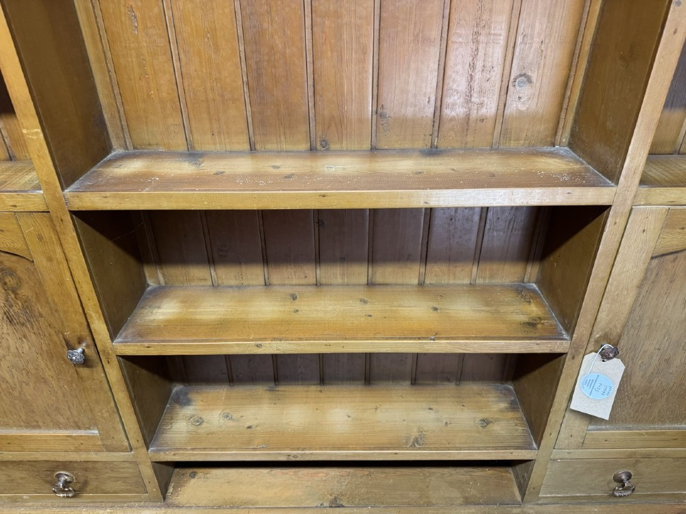 A two-part antique pine Welsh dresser featuring an open plate rack flanked by small side cupboards above three frieze drawers and an open pot board base. View XIV