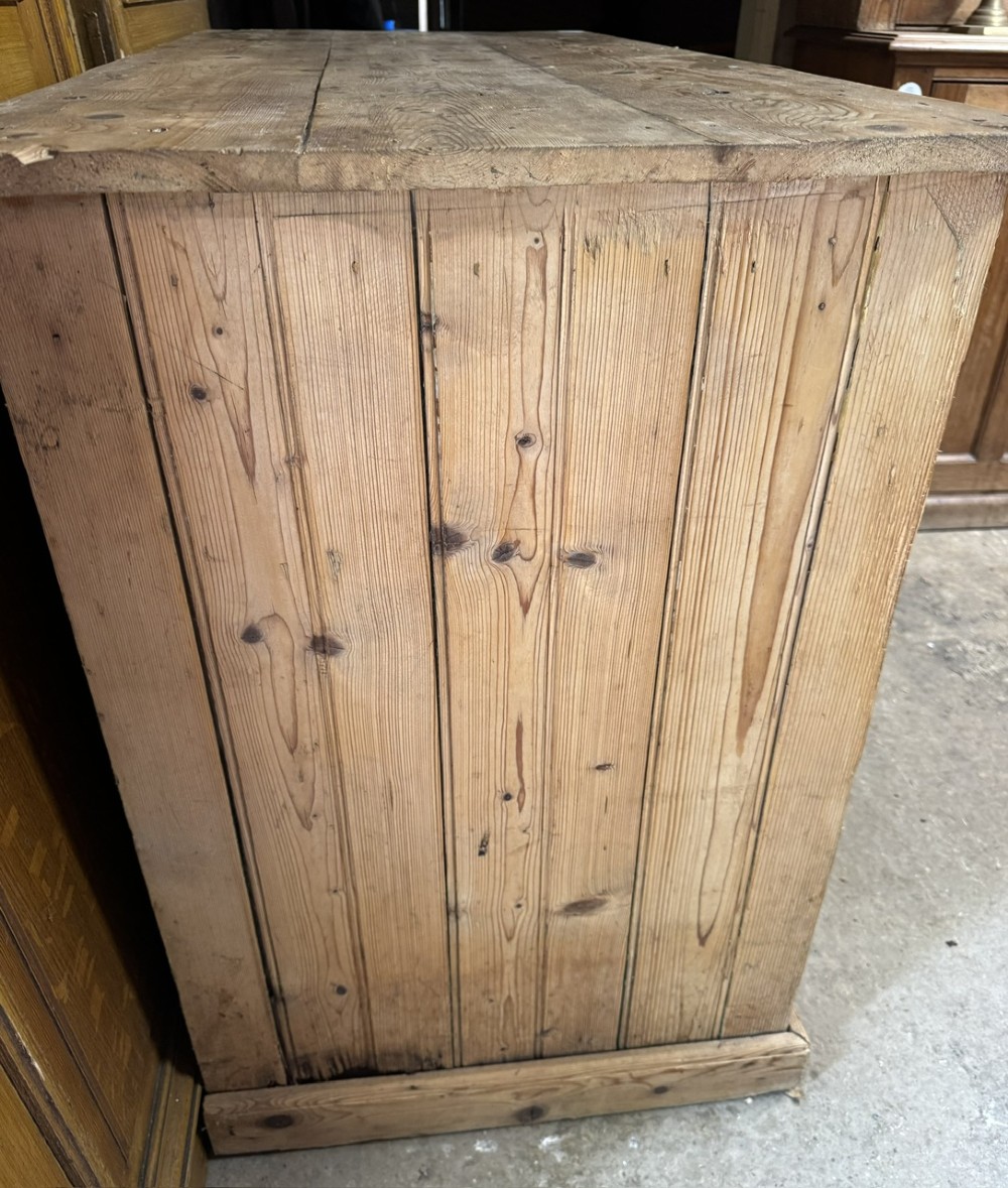 An antique country pine low cupboard featuring three top drawers over three panelled cupboard doors with turned wooden handles. View V