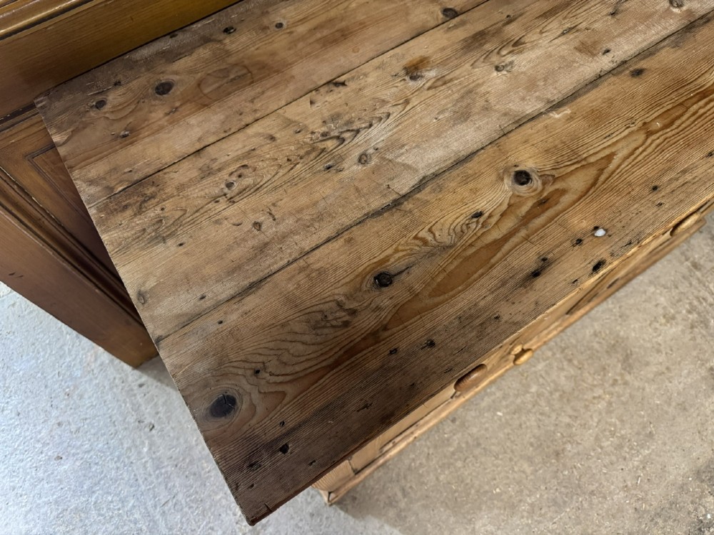An antique country pine low cupboard featuring three top drawers over three panelled cupboard doors with turned wooden handles. View X