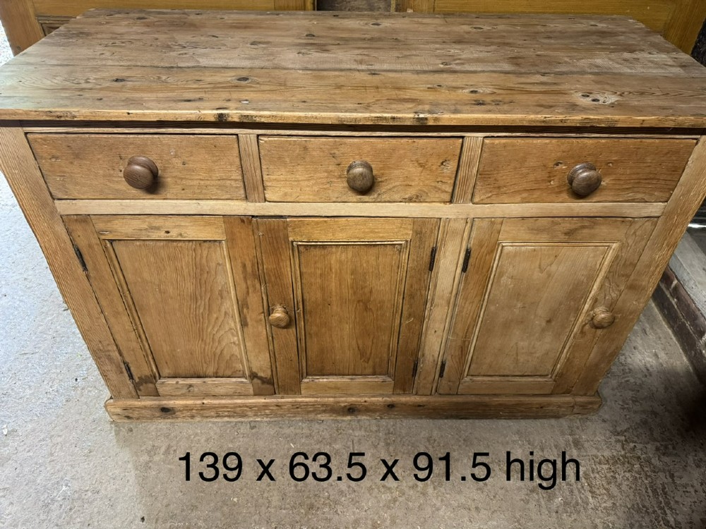 An antique country pine low cupboard featuring three top drawers over three panelled cupboard doors with turned wooden handles. View XI