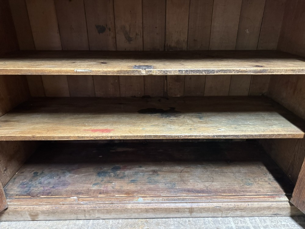 A two-tier nineteenth-century pine school cabinet featuring panelled double doors, brass catches, and a natural waxed finish. View VI