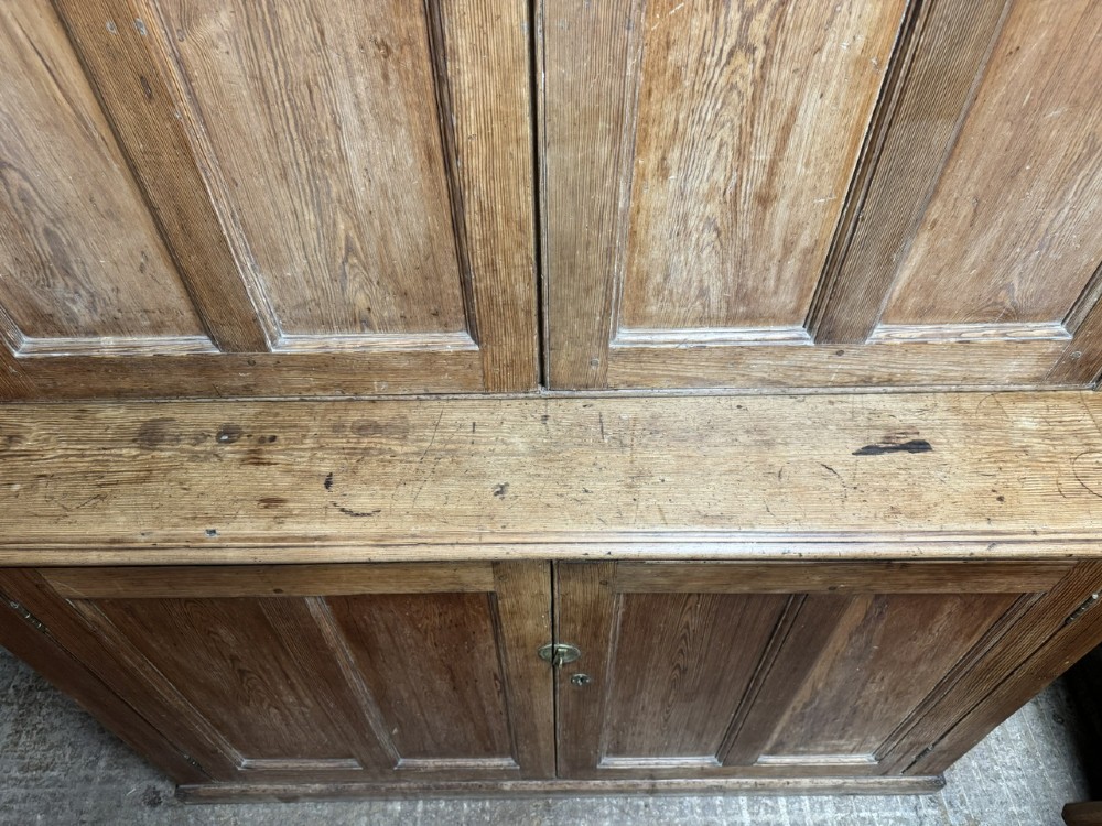 A two-tier nineteenth-century pine school cabinet featuring panelled double doors, brass catches, and a natural waxed finish. View X
