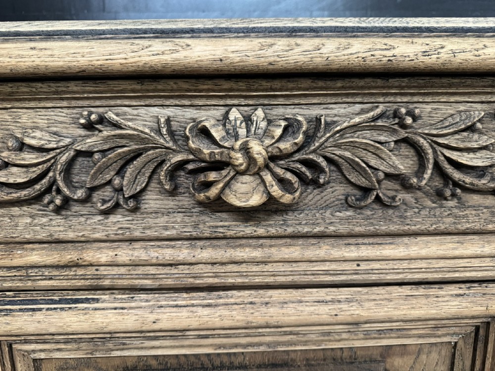A three-door carved light oak sideboard featuring detailed relief panels depicting artistic and musical instruments. View XII