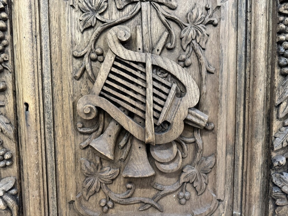 A three-door carved light oak sideboard featuring detailed relief panels depicting artistic and musical instruments. View XIII