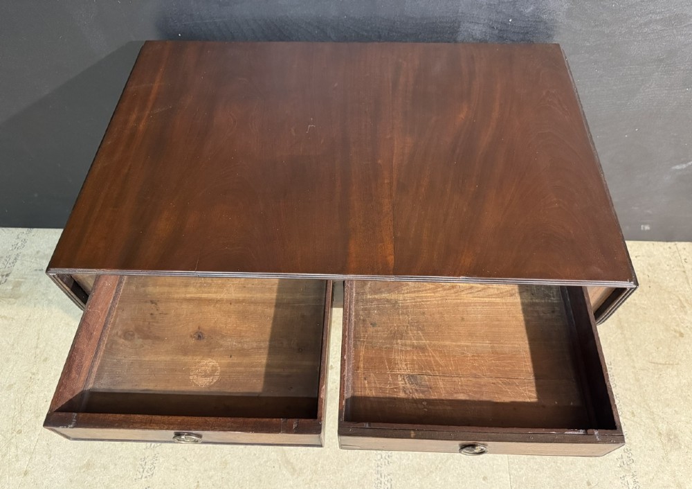A Georgian style dark mahogany sofa table featuring two drawers with brass ring pulls, drop leaves on either side, and reeded tapered legs on brass castors. View V