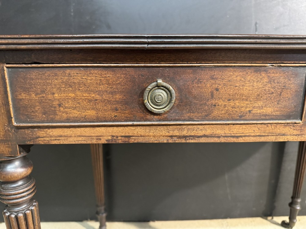 A Georgian style dark mahogany sofa table featuring two drawers with brass ring pulls, drop leaves on either side, and reeded tapered legs on brass castors. View VIII