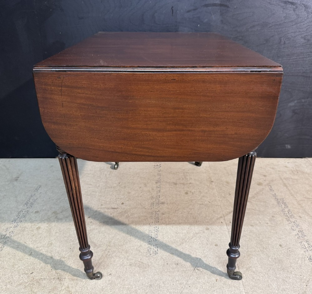 A Georgian style dark mahogany sofa table featuring two drawers with brass ring pulls, drop leaves on either side, and reeded tapered legs on brass castors. View XIII