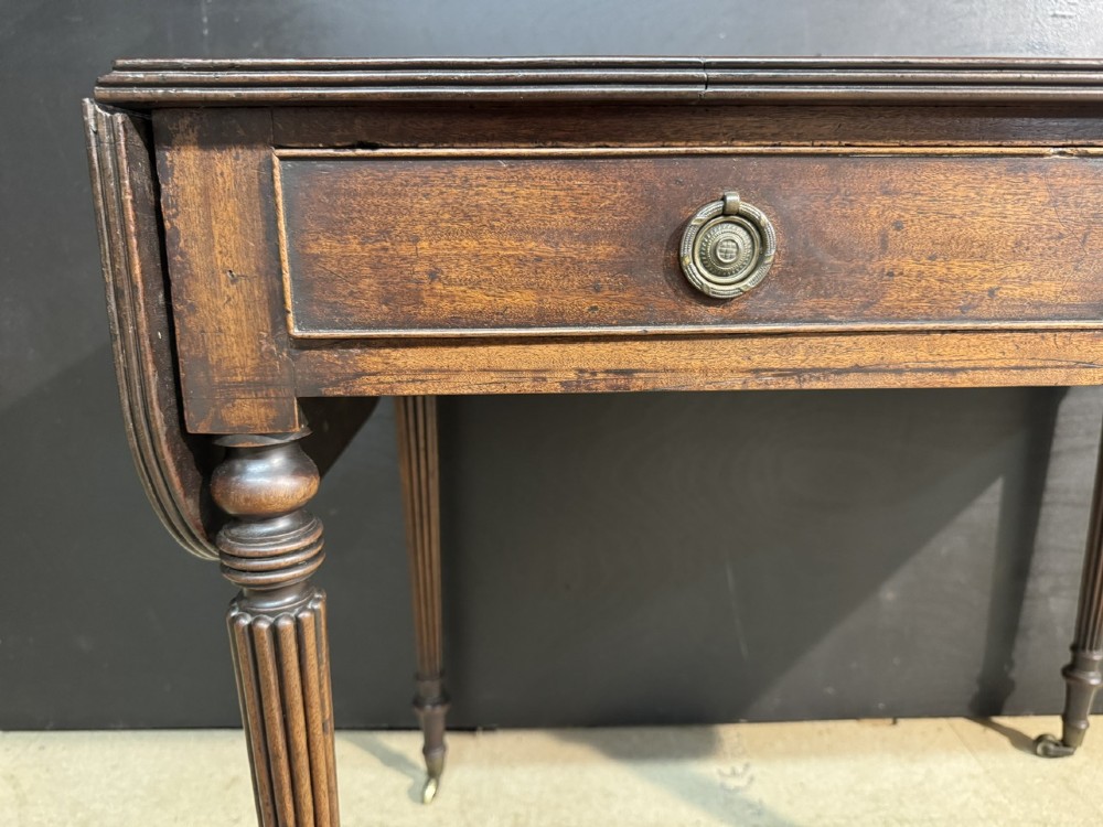 A Georgian style dark mahogany sofa table featuring two drawers with brass ring pulls, drop leaves on either side, and reeded tapered legs on brass castors. View XIV