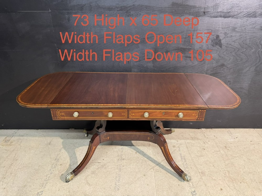 A Georgian mahogany sofa table featuring two inline drawers with satinwood string inlay, drop leaves, twin-pillar supports, and splayed legs ending in brass claw feet on castors. View XIV