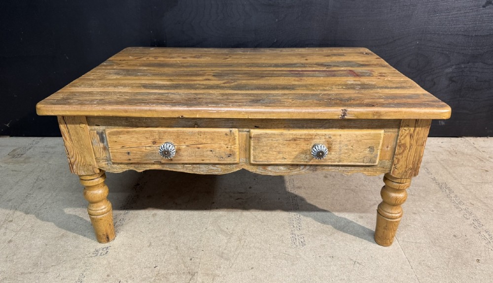 A rectangular rustic pine coffee table featuring a plank top, two front drawers with decorative ceramic knobs, and four turned wooden legs. View II