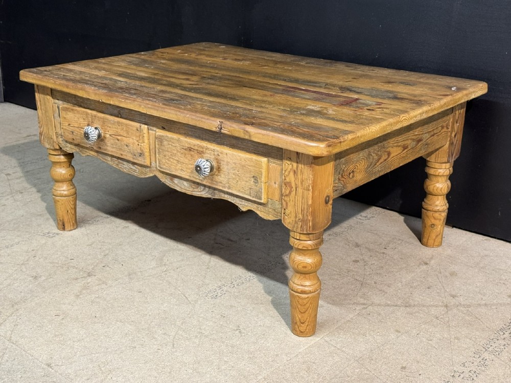 A rectangular rustic pine coffee table featuring a plank top, two front drawers with decorative ceramic knobs, and four turned wooden legs. View VI